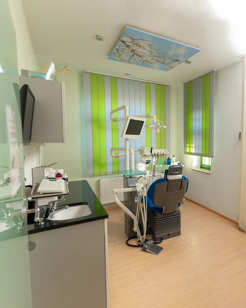 Behandlungszimmer mit grünen Lamellen und Himmelsbild an der Decke